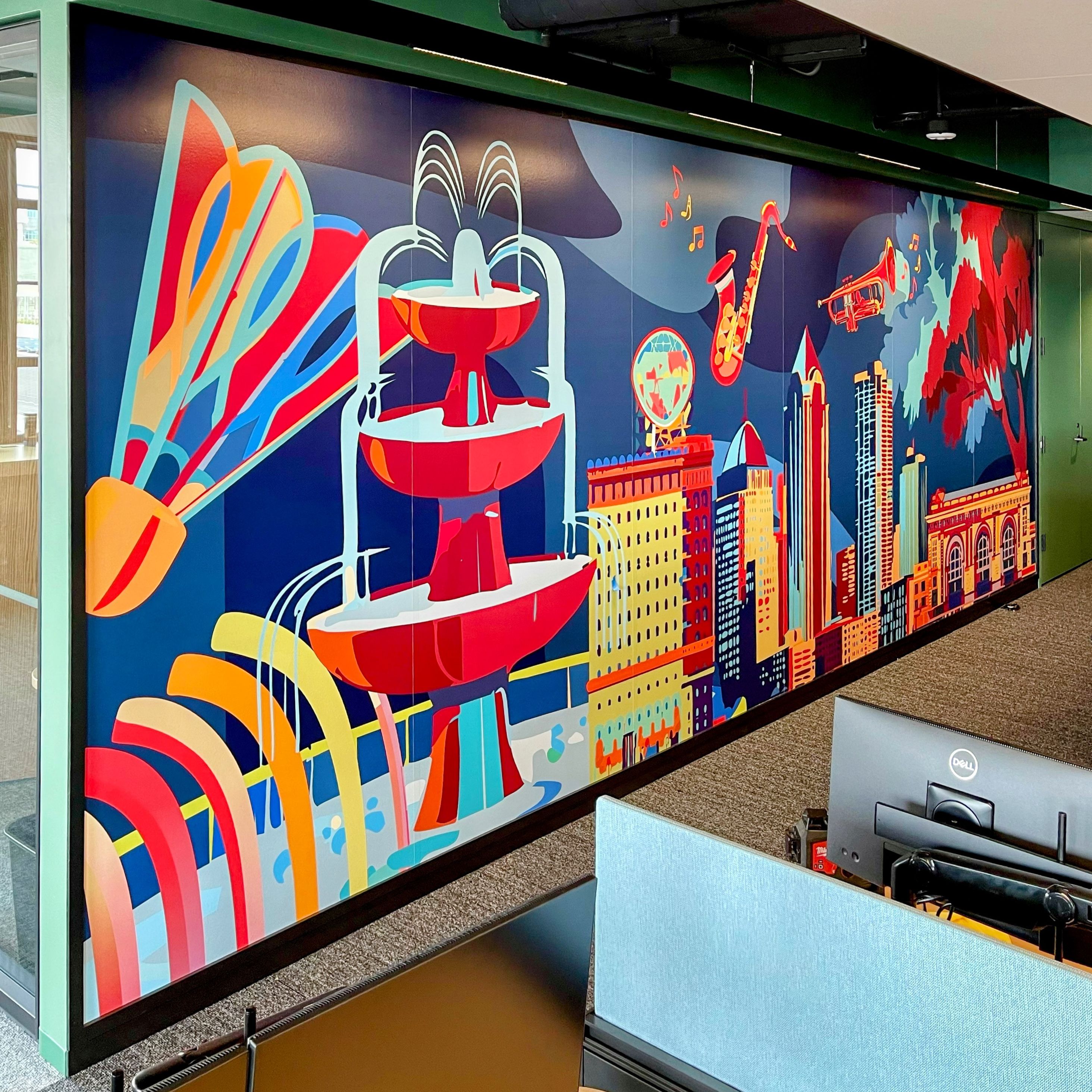 A colorful wall graphic depicts various Kansas City-themed icons, including a fountain, the skyline, and jazz instruments.