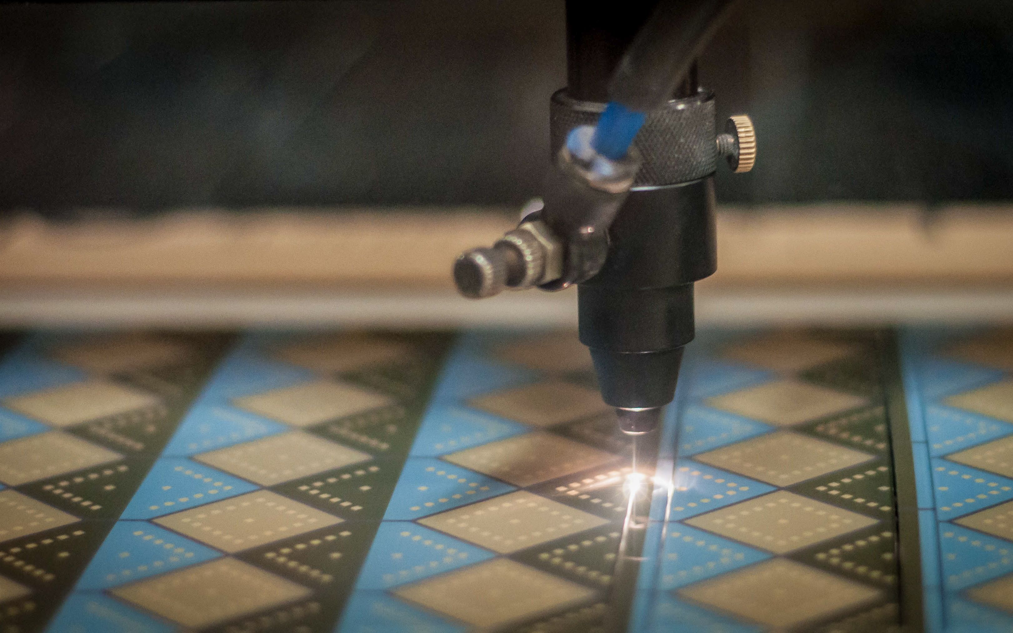 A laser cutting machine is cutting a piece of acrylic with a printed pattern on it.