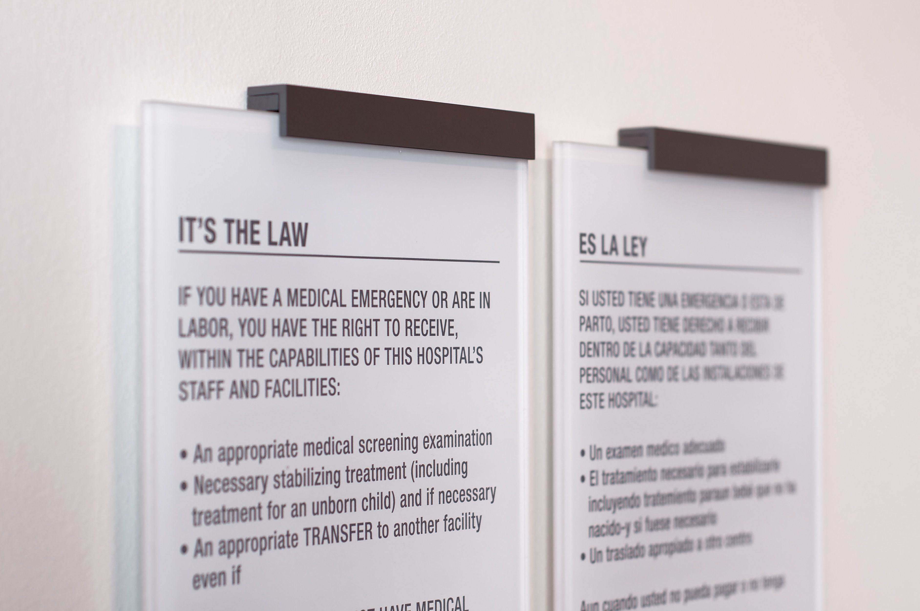 A pair of legal compliance signs in English and Spanish describe patient rights in a hospital.