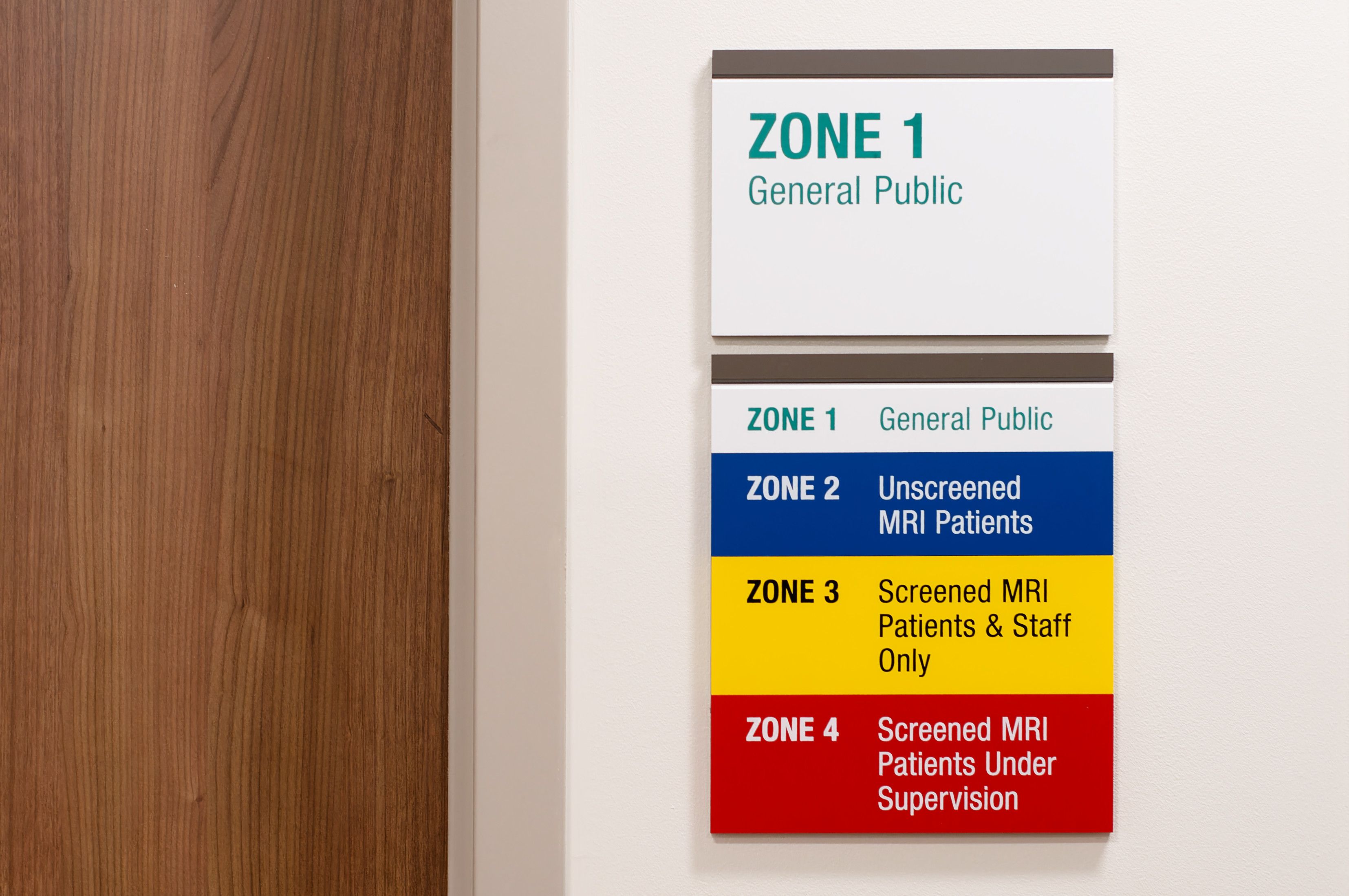 Two MRI safety signs mounted on a wall. One describes the various MRI safety zones, and the other indicates which zone the sign is located in.