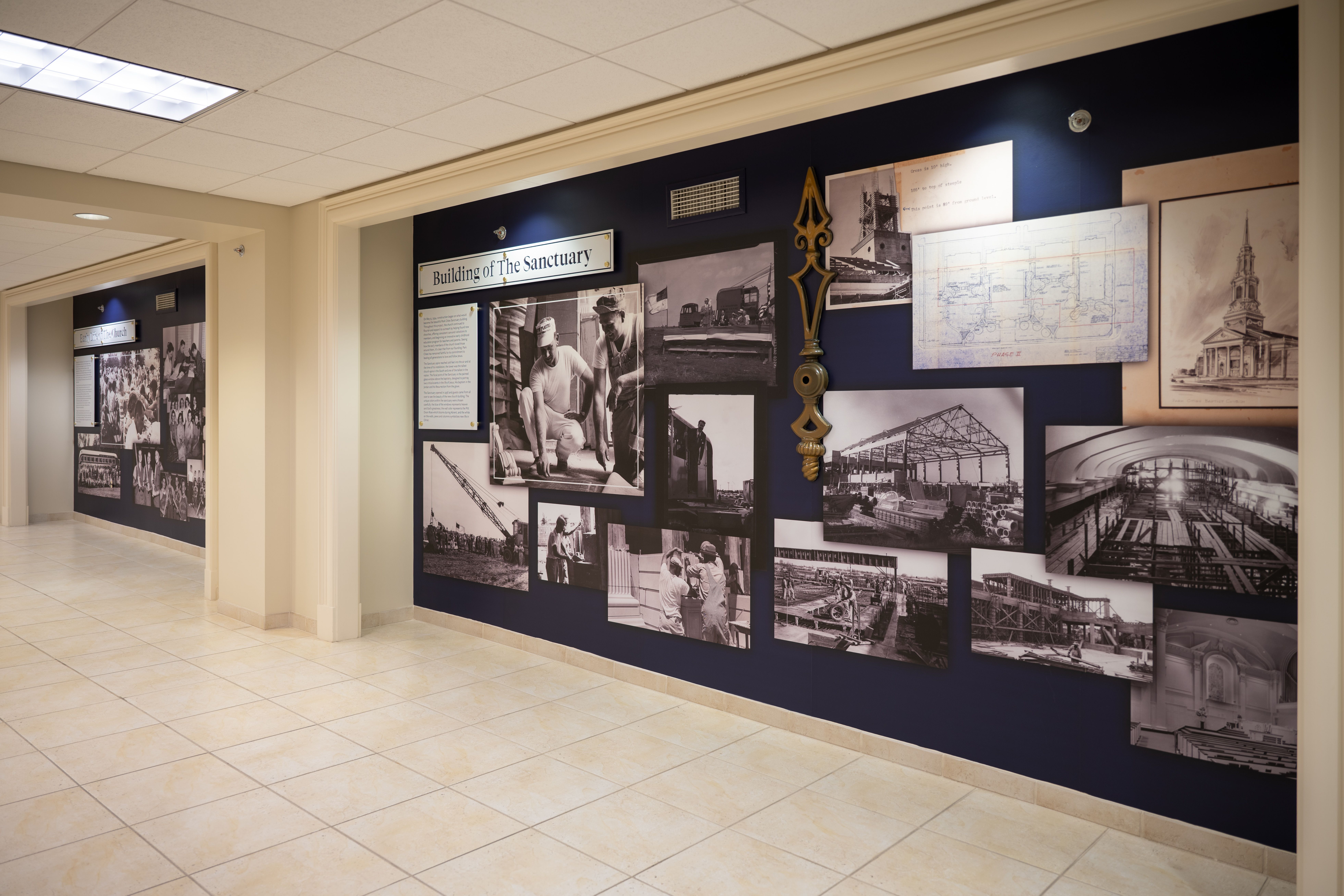 Two inset nooks in a church hallway are decorated with printed wall graphics showing photographs and artifacts from the church's history. Laser-cut acrylic panels with text are mounted in front of the graphics, describing the images.