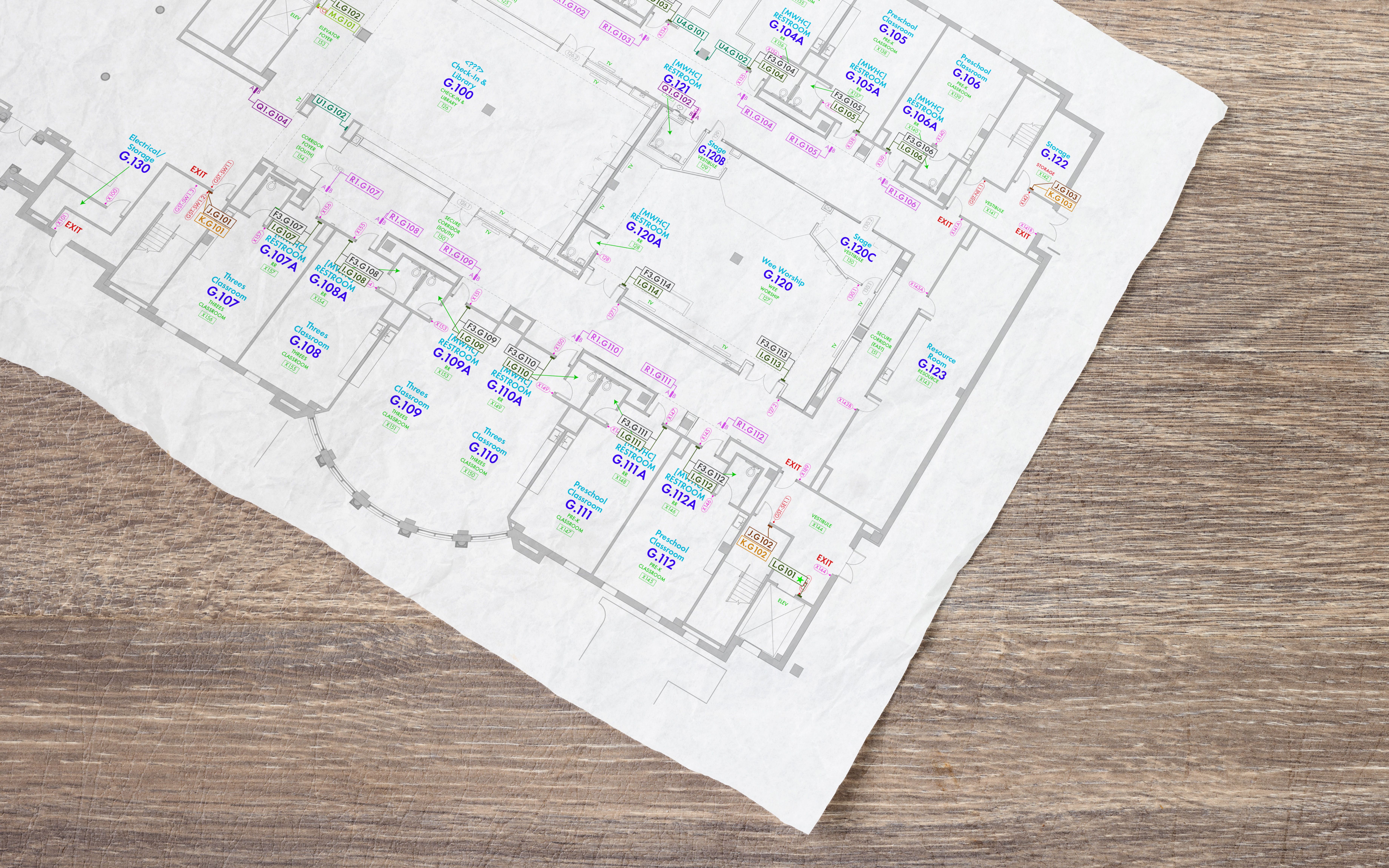 A sheet of paper with a floor plan shows new sign locations and room names.