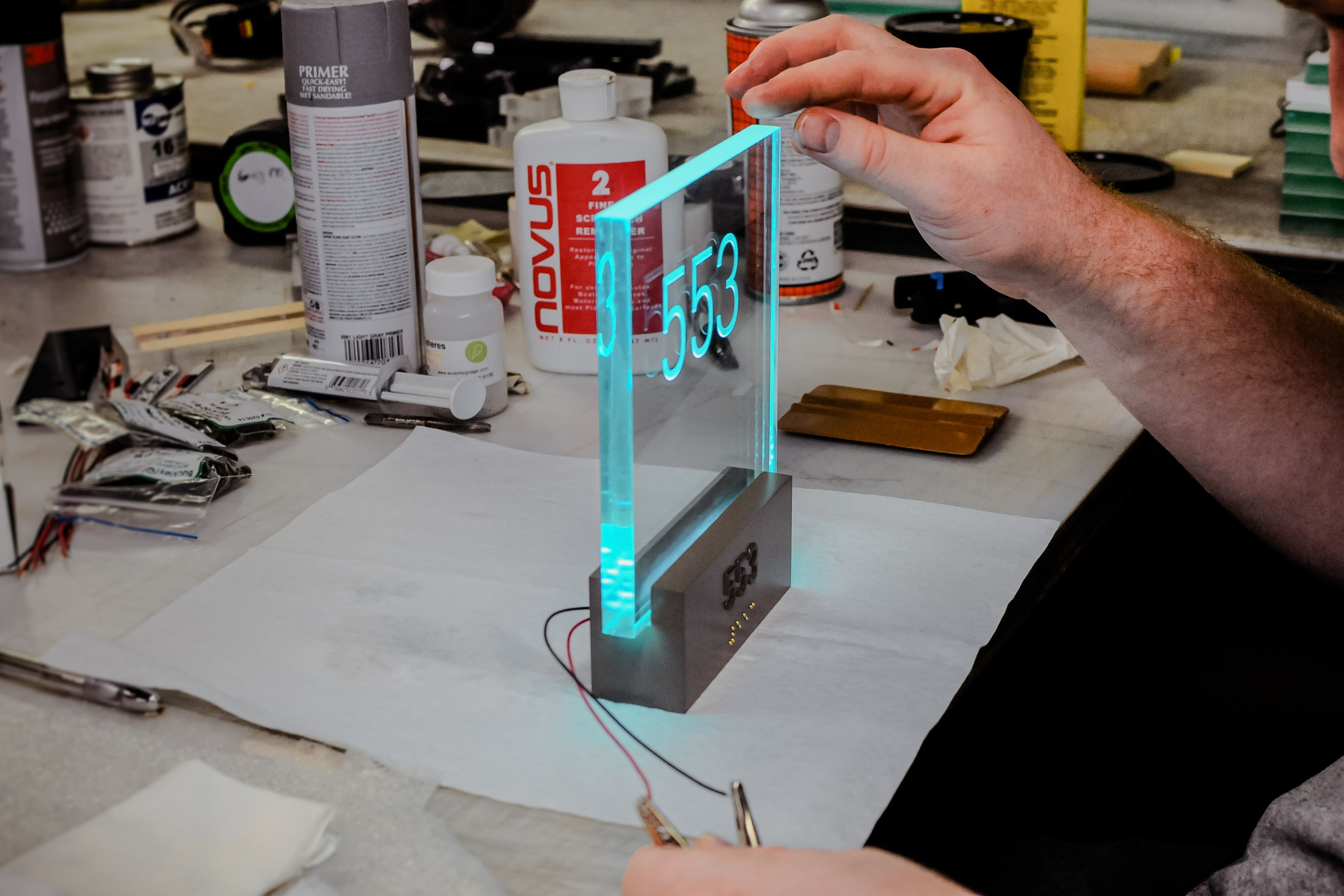 A production member inspects a prototype of an illuminated hotel room sign to make sure the LED lighting is functioning correctly.