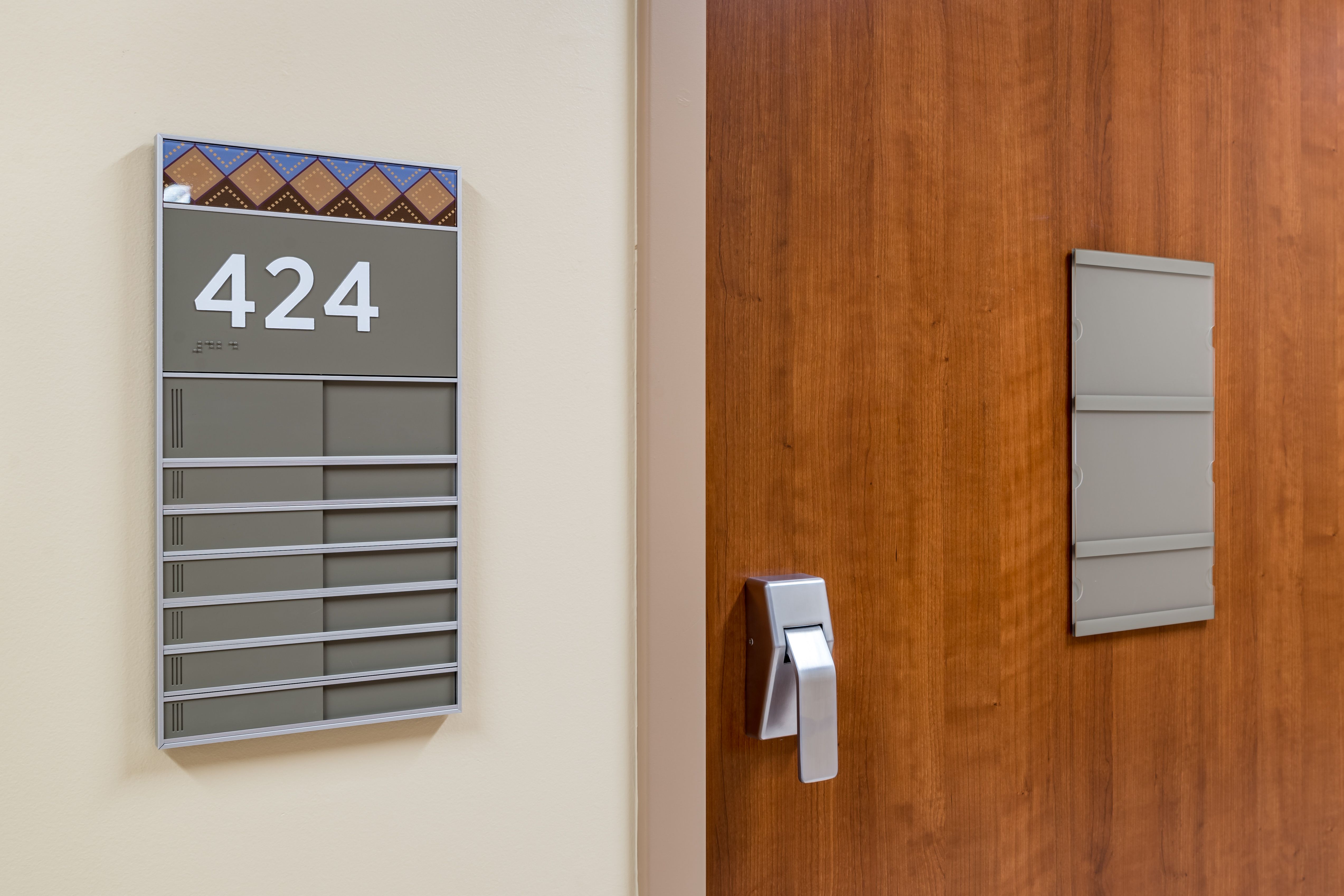 A combined elevator evacuation map sign and directory listing level destinations are mounted next to an elevator call button. The sign has brushed brass accents and indicates the viewer is in the "Collins Building"