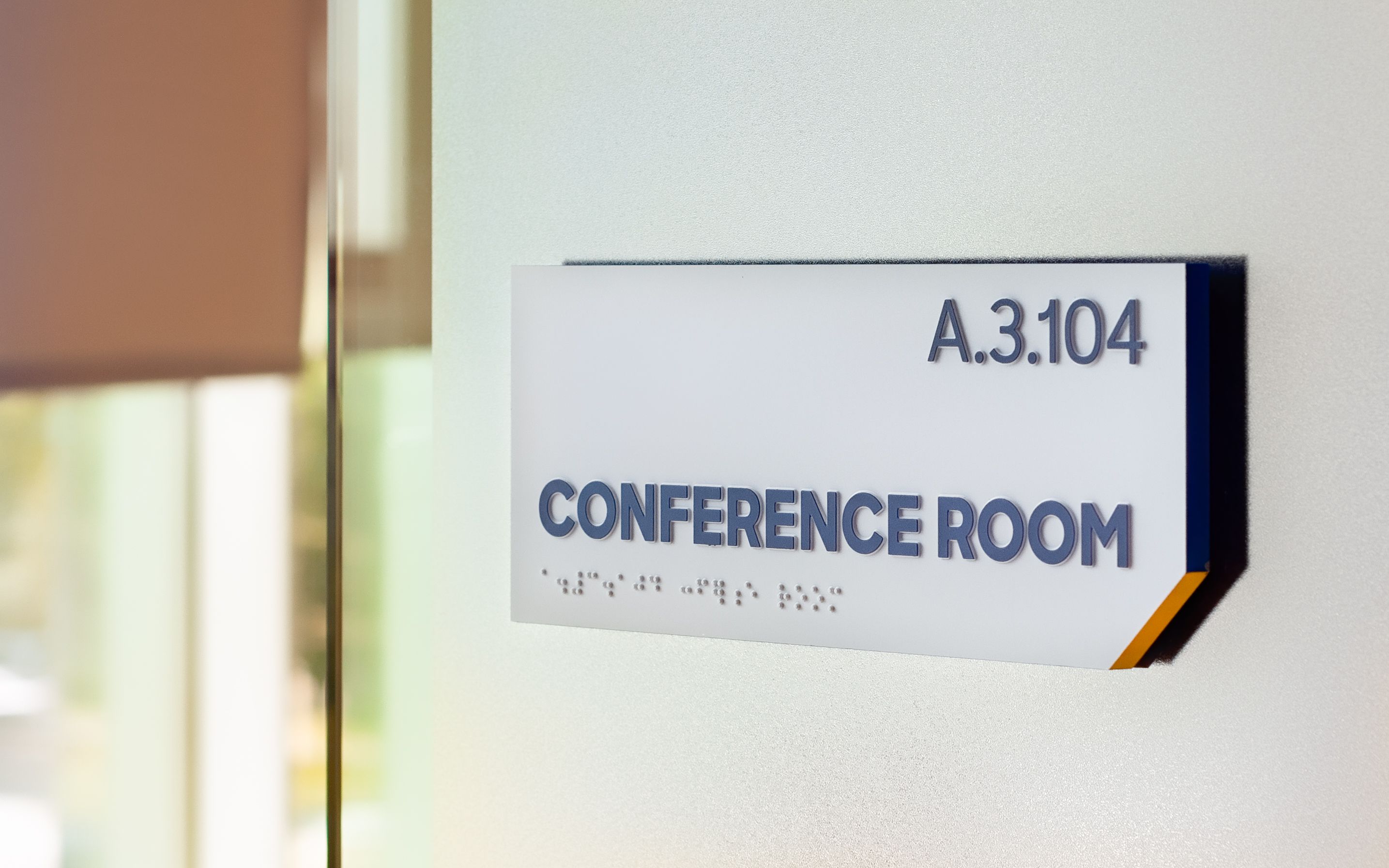 Two directional signs located above a set of doors in a hallway point to hospital departments.