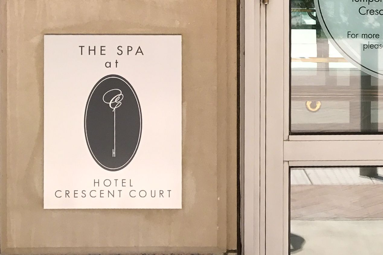 An aluminum sign with a screenprinted spa logo mounted next to the spa entrance.